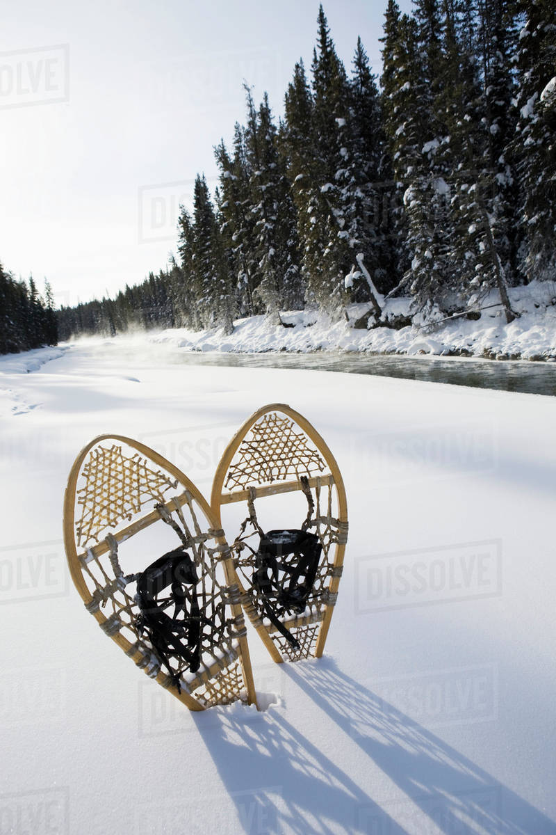 Snowshoes By River; Lake Louise, Alberta, Canada Stock Photo Dissolve