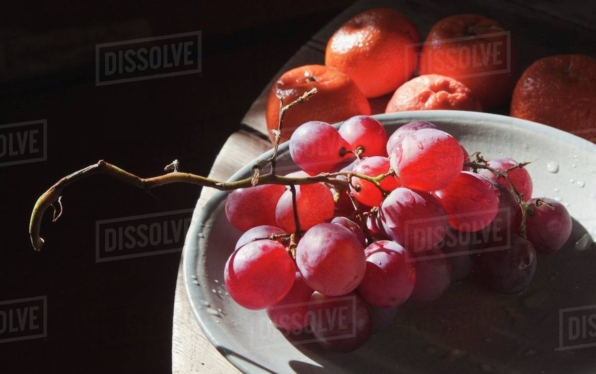 Fruit; Red Grapes On Plate With Mandarins In Background Stock Photo
