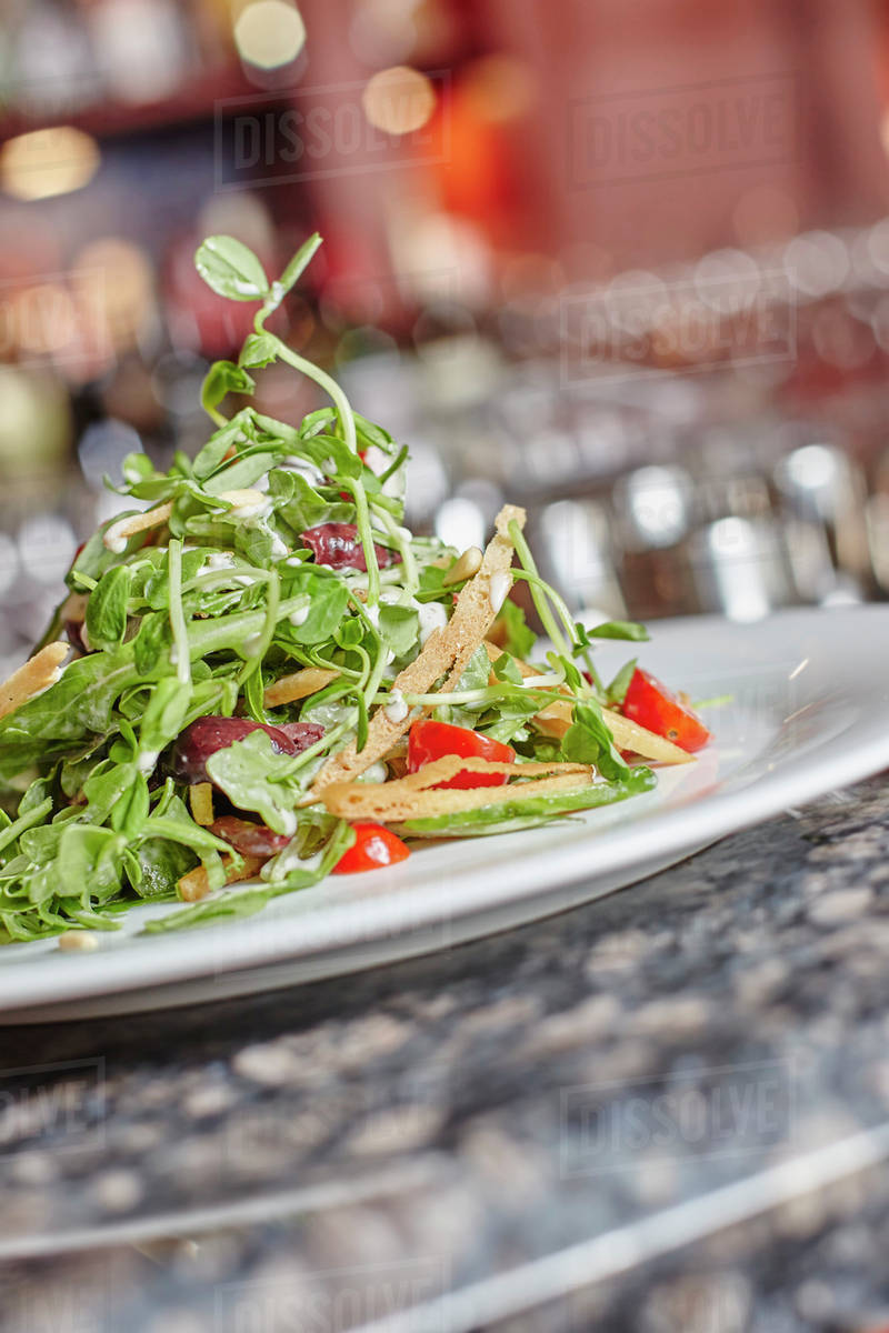 Plated salad with pancetta, cherry tomato, bread crisps, pine nuts, and