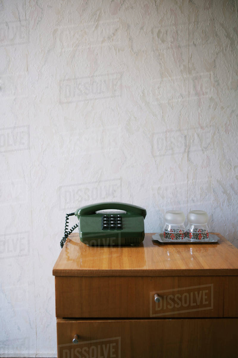 Hotel nightstand with pushbutton phone and water glasses, textured