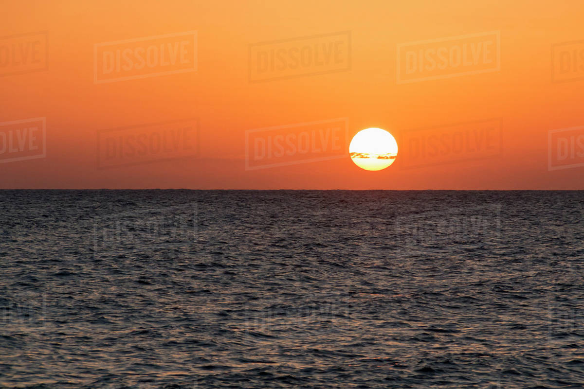 Glowing sun over the ocean and horizon at sunset; Paphos, Cyprus - Stock Photo - Dissolve