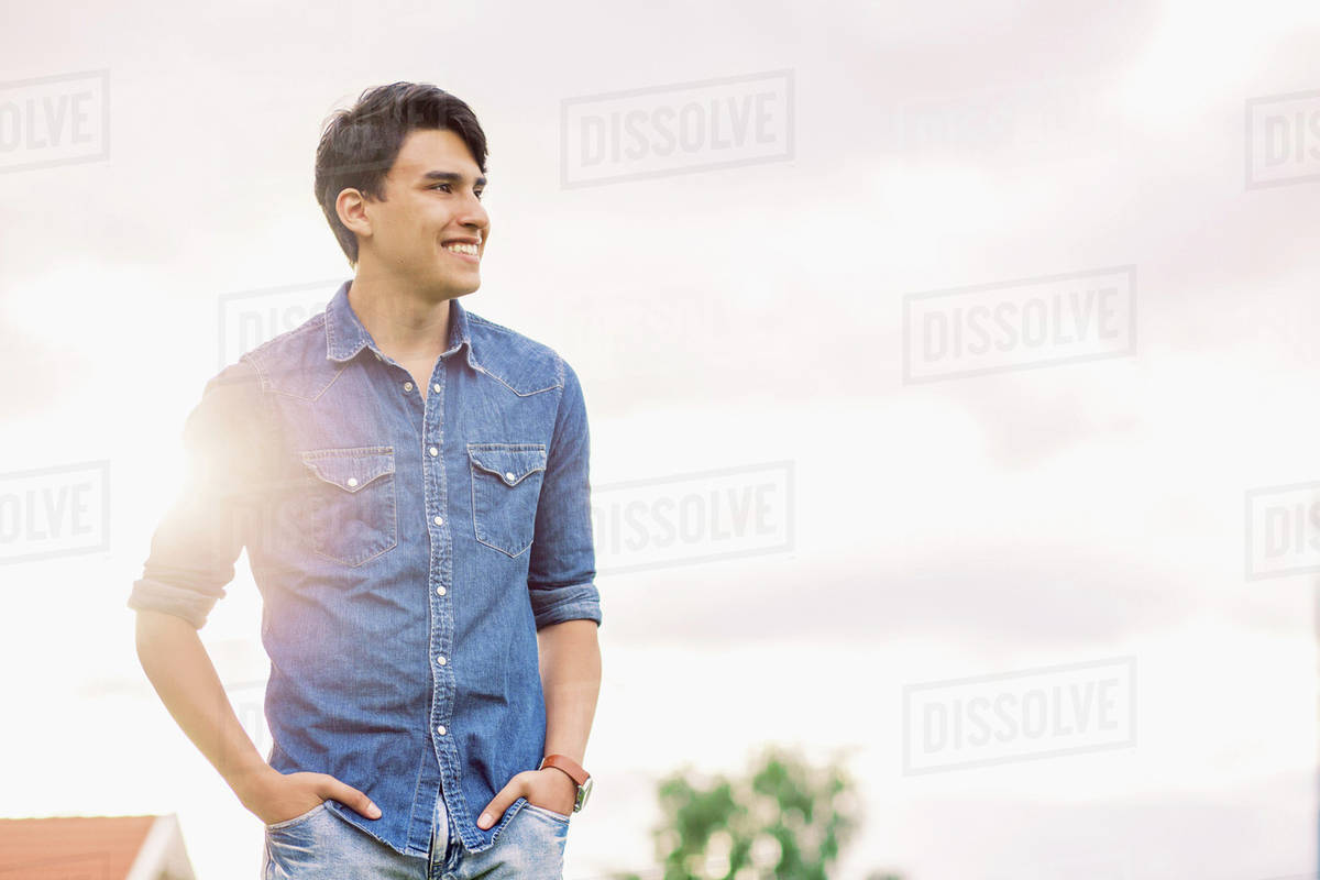 Happy young man with hands in pockets standing against sky Royalty-free stock photo