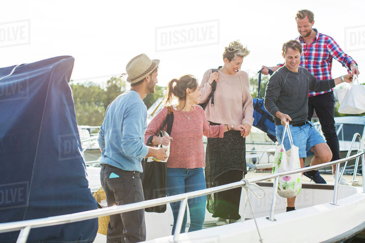 Happy friends boarding yacht against sky Stock Photo Dissolve