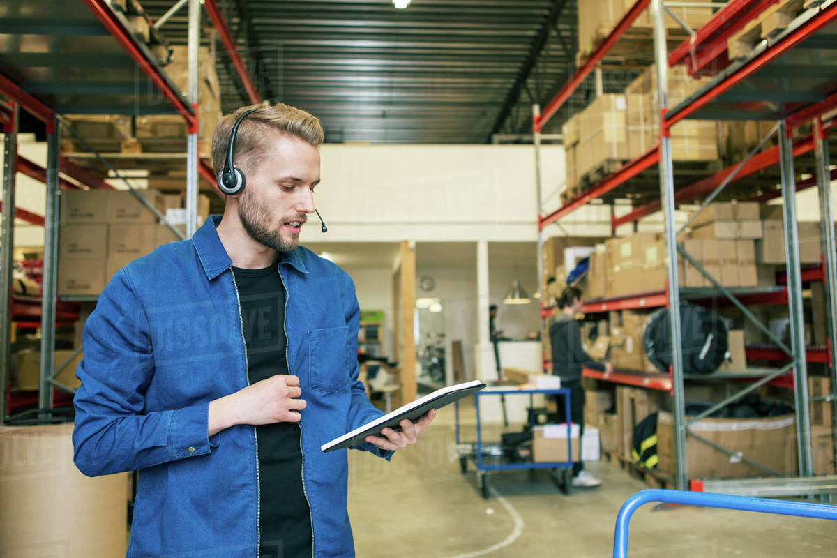 Confident manual worker wearing headphones while using digital tablet