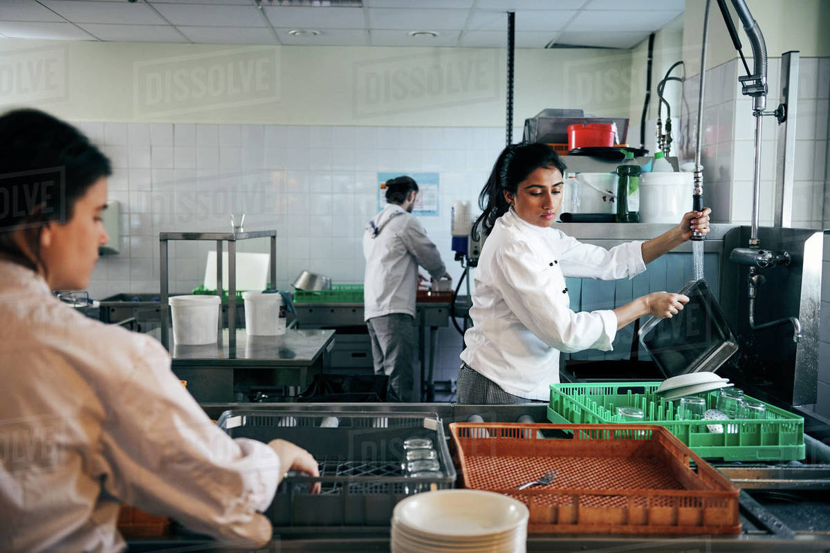 Female chef washing dishes in commercial kitchen Stock Photo Dissolve