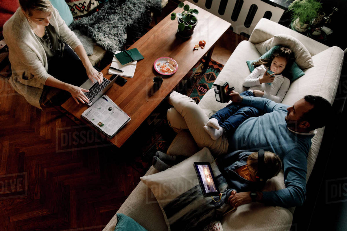 High angle view of family using various technologies in living room at home Royalty-free stock photo