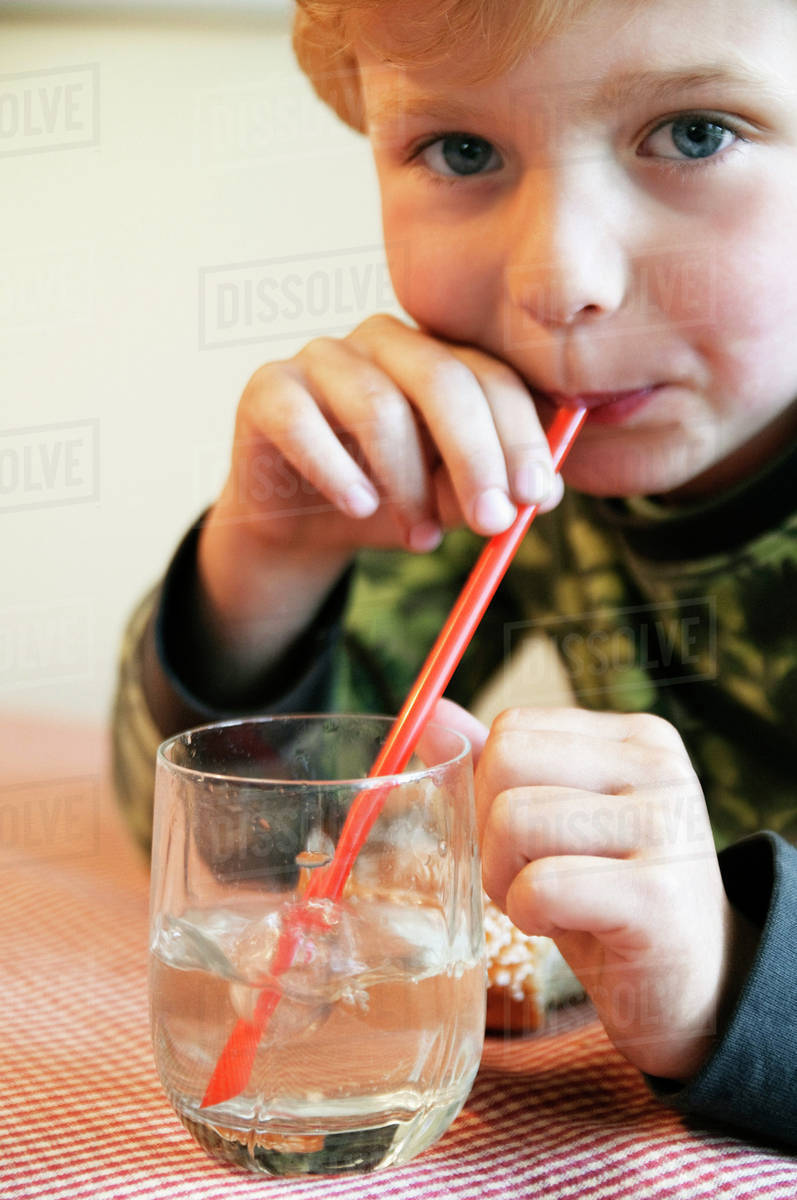 Closeup on boy blowing in a straw Stock Photo Dissolve