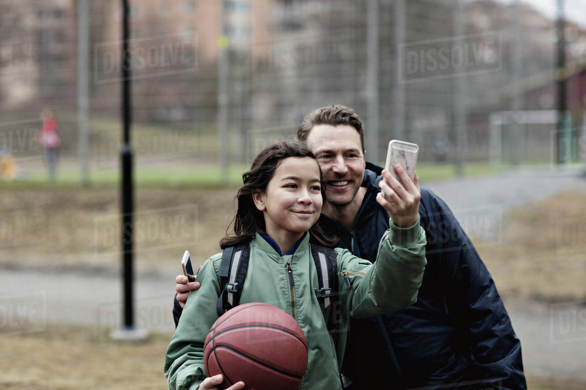 Smiling son taking selfie with father after basketball practice in winter Royalty-free stock photo