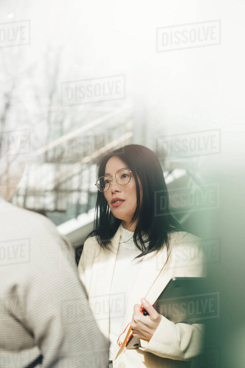 Female executive discussing with colleague in office seen through window Royalty-free stock photo