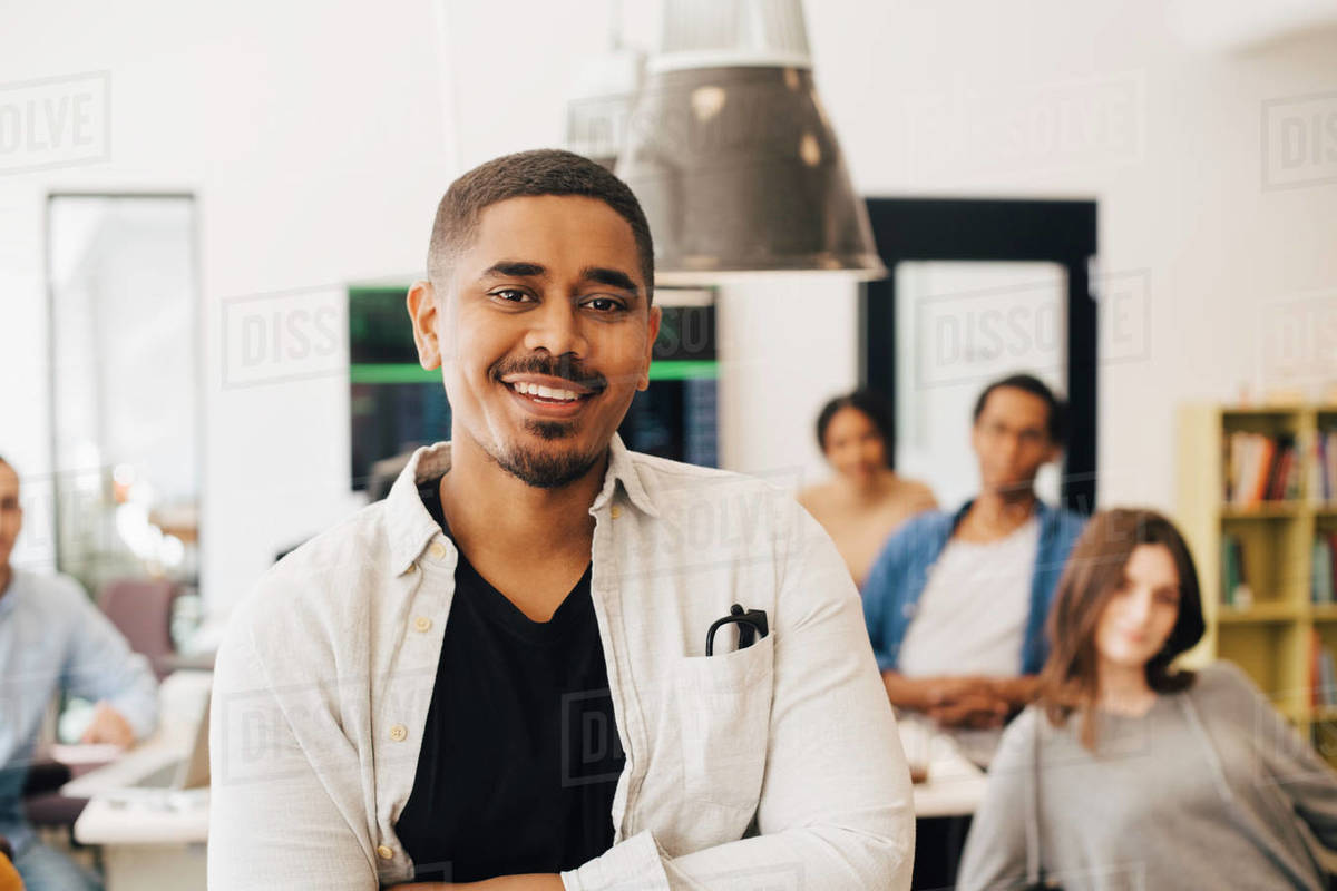 Portrait of smiling computer programmer standing with colleagues in ...