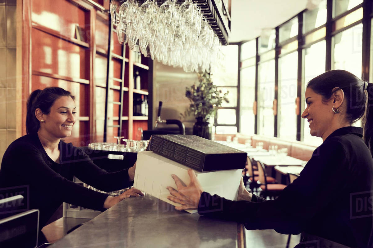 Smiling owner and coworker with modem box at checkout counter in cafe Royalty-free stock photo