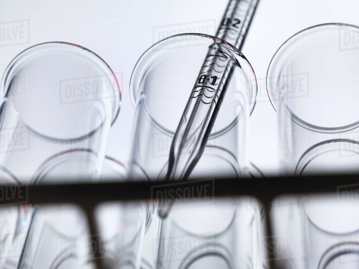 Low angle view of graduated pipette pipetting liquid into test tube