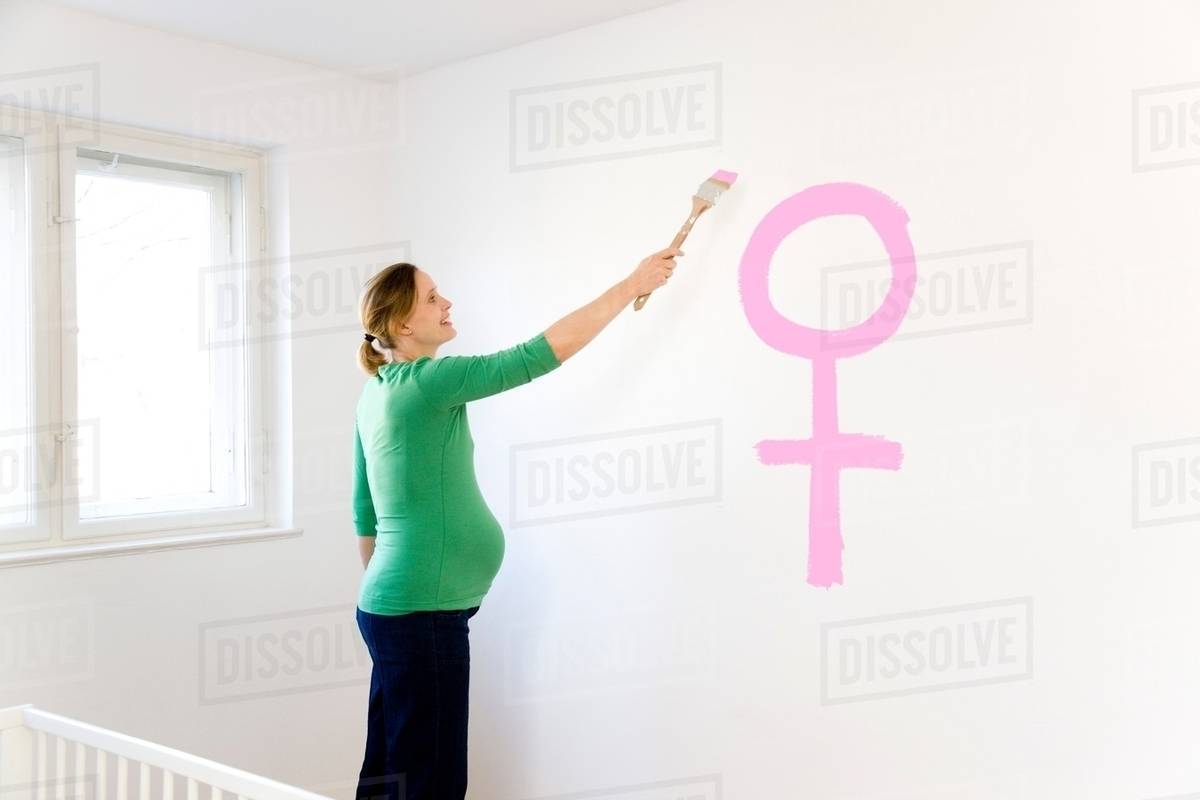 Pregnant woman painting nursery Stock Photo Dissolve