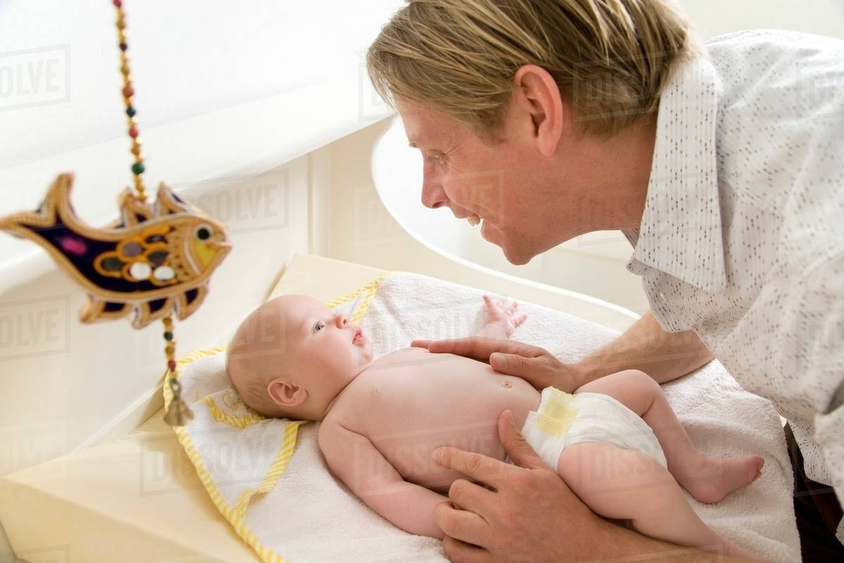Father changing baby's nappy Stock Photo Dissolve