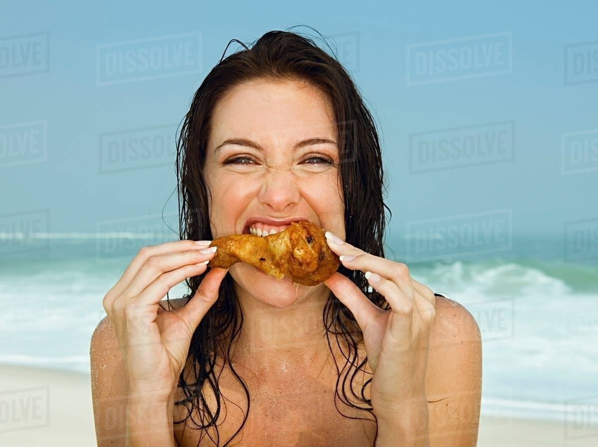 Young women eating a chicken leg Stock Photo Dissolve