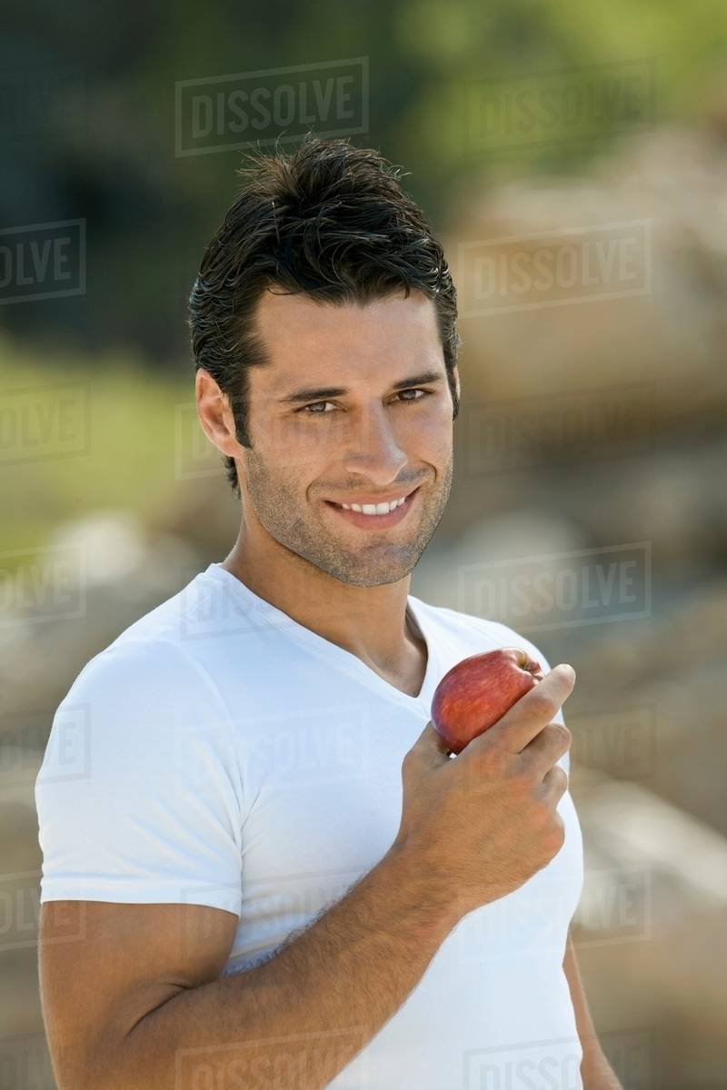 A latin male holding an apple smiling Stock Photo Dissolve