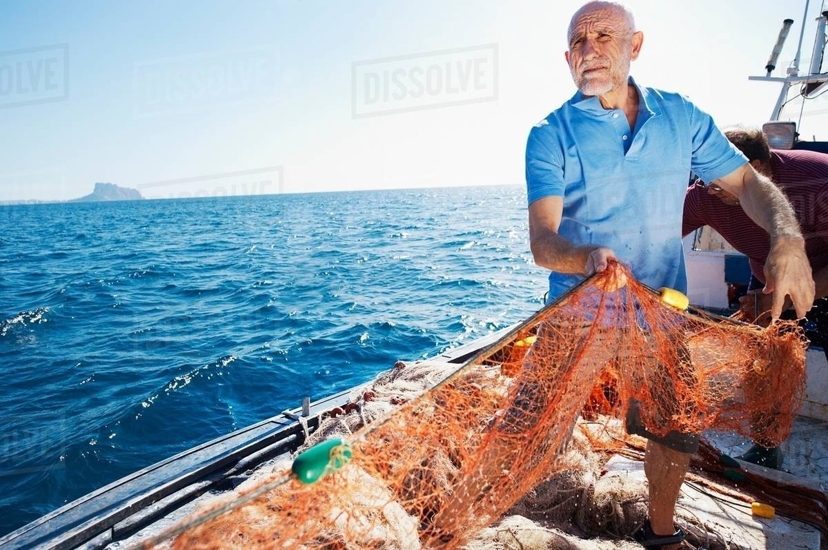 Fisherman on boat pulling in nets Stock Photo Dissolve