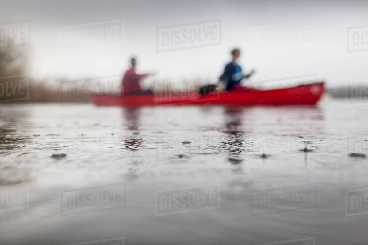 Two people canoeing in rain Stock Photo Dissolve