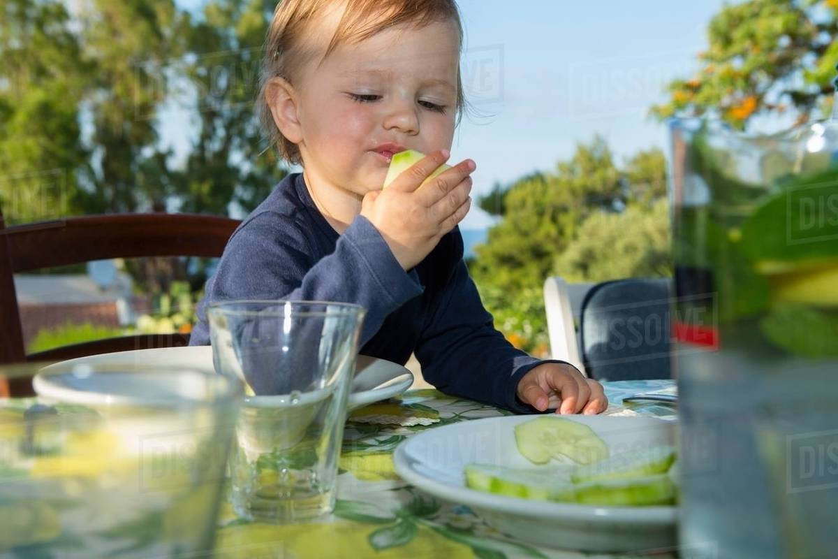 Female toddler eating at table outdoors Stock Photo Dissolve
