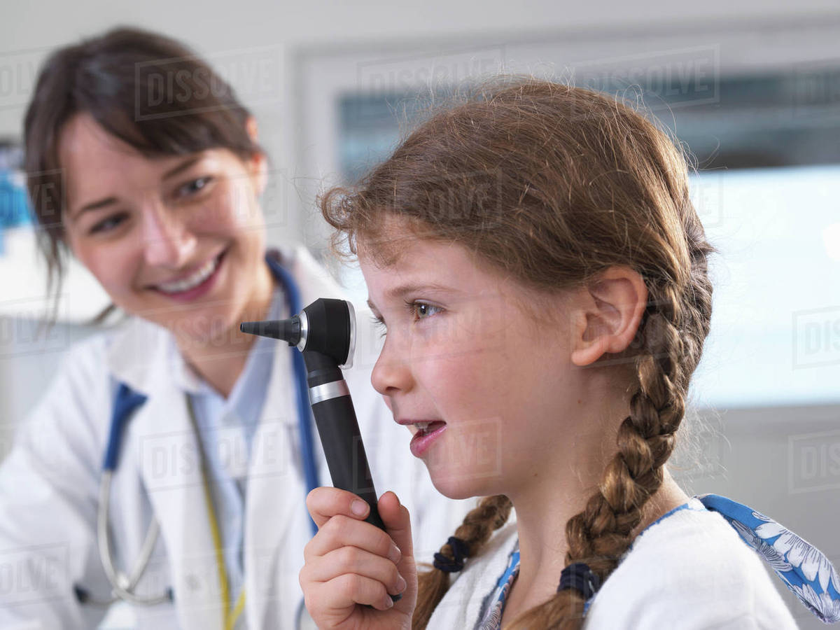 Girl looking through otoscope Stock Photo Dissolve