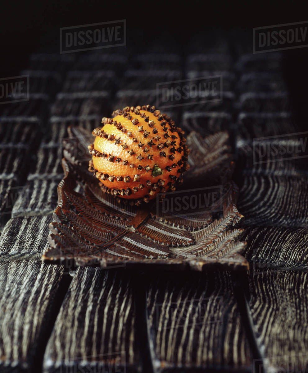Orange with cloves stuck in, on vintage wooden plate Stock Photo