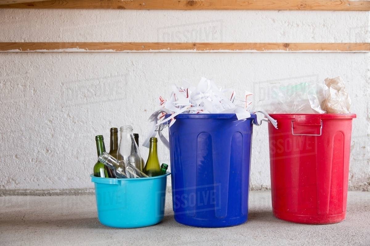 Three recycling buckets in garage with bottles, paper and plastic