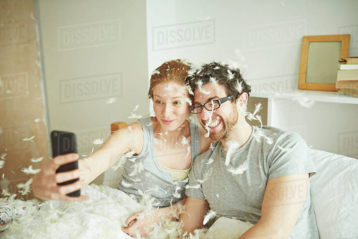 Mid Adult Couple Covered In Pillow Fight Feathers Taking