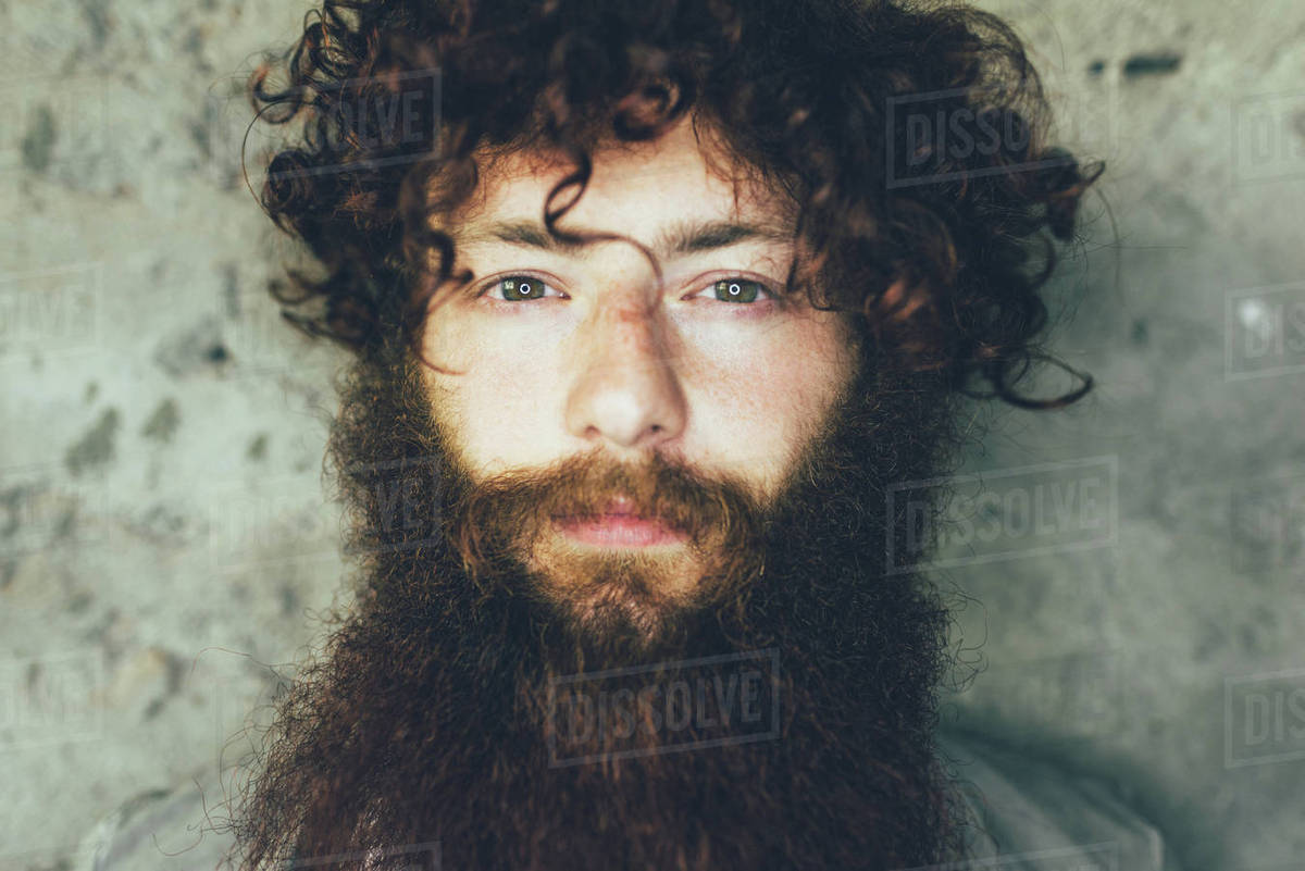 Close Up Portrait Of Young Male Hipster With Brown Curly Hair And