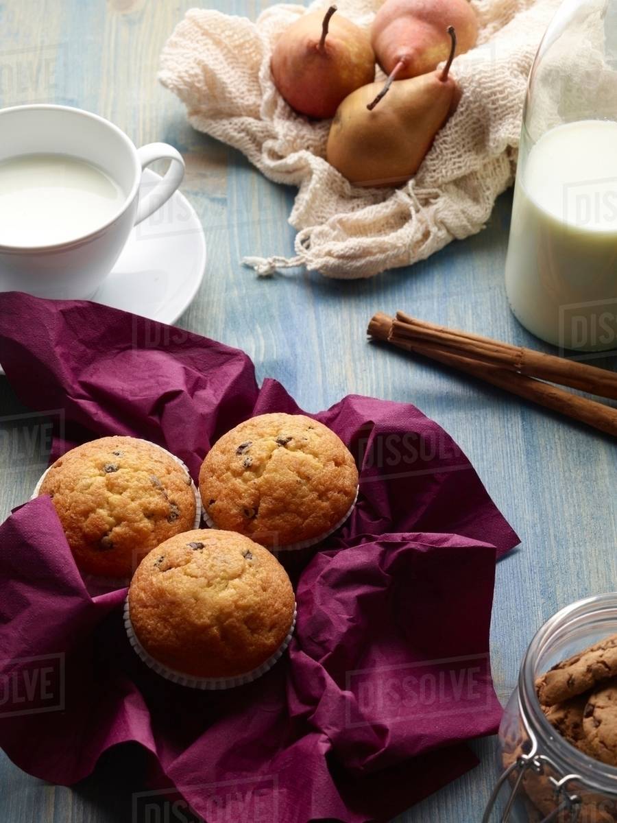 Muffins, pears, and milk on table Stock Photo Dissolve