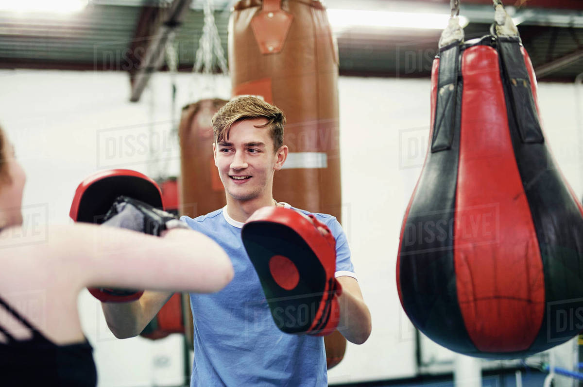 Female boxer training, punching teammate's punch mitt Stock Photo