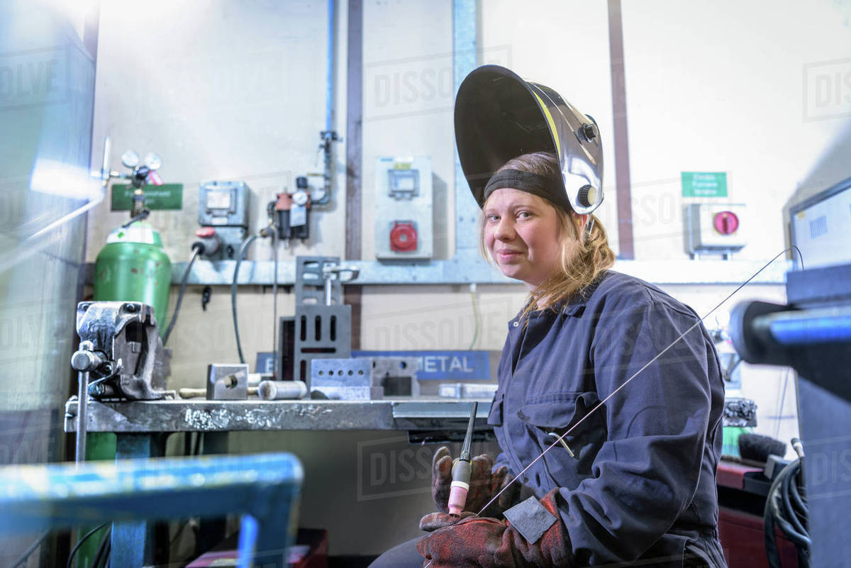 female apprentice welder holding equipment in car factory portrait apprentice welder