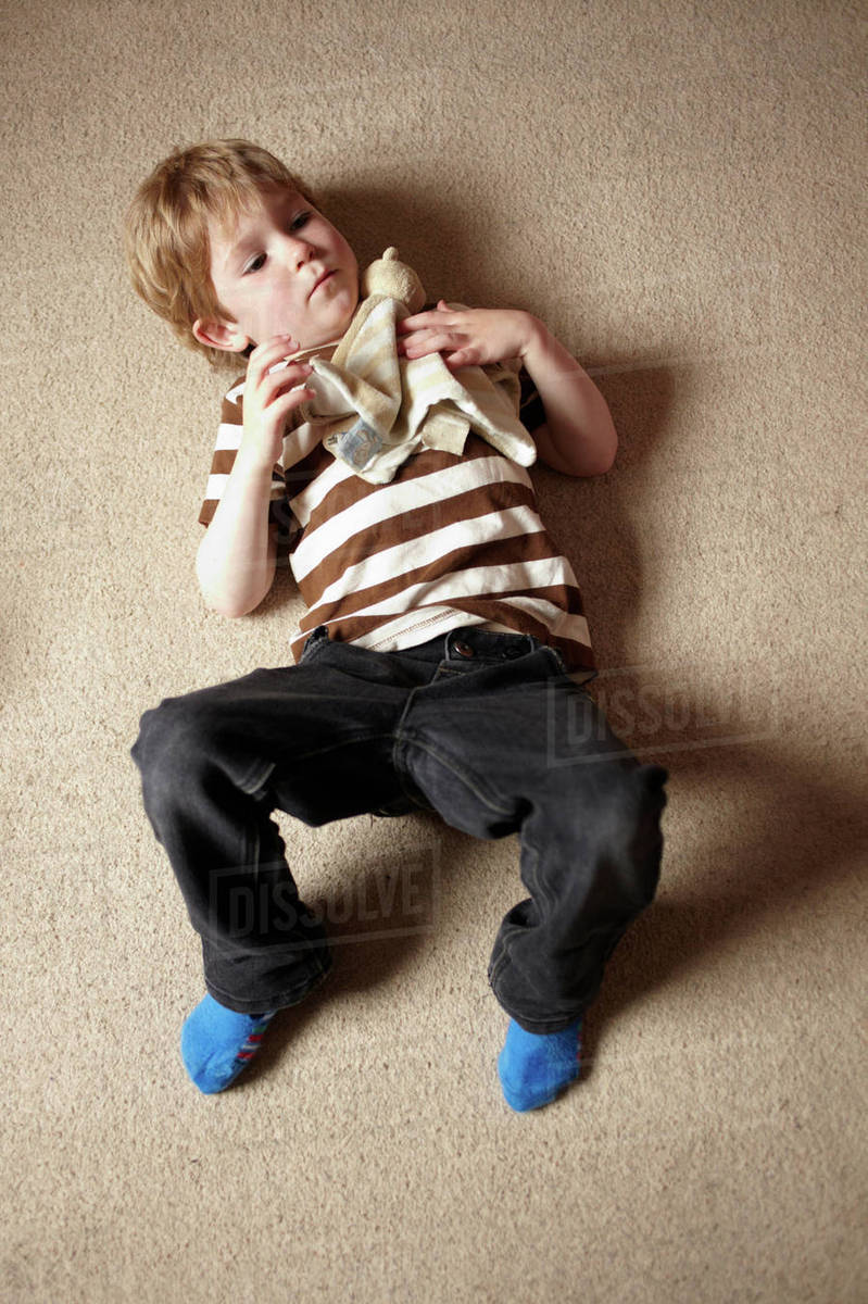 Boy laying on carpeted floor Stock Photo Dissolve