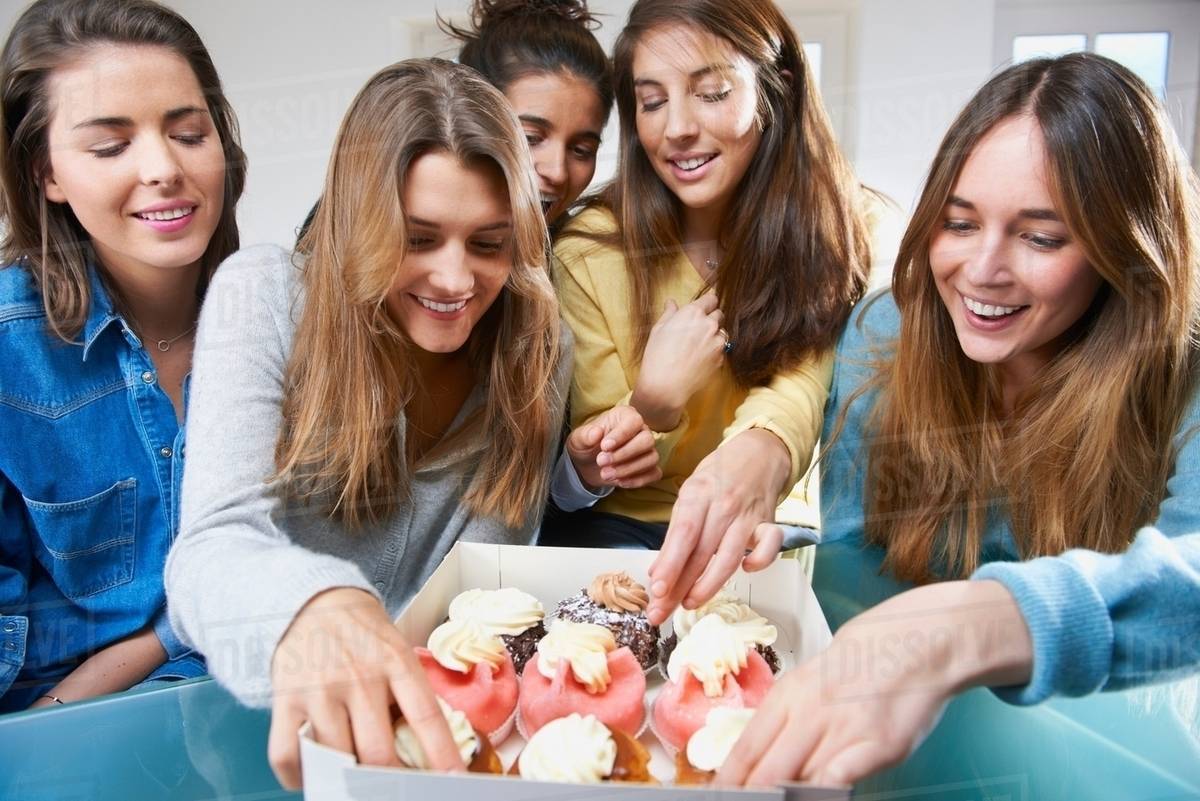 Women eating cupcakes together Stock Photo Dissolve