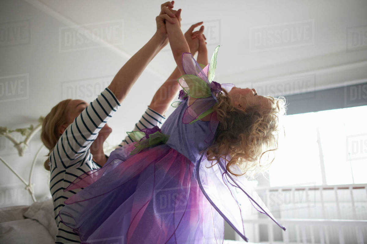Young girl dressed in fairy costume, holding hands with mother, leaning back Royalty-free stock photo