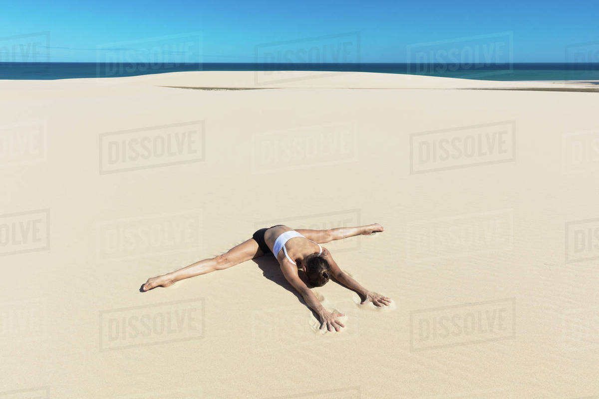 Woman on beach in yoga position, bending forward doing the splits Stock Photo Dissolve