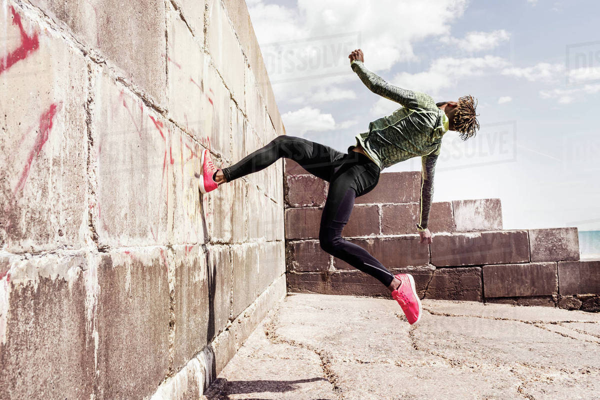Young man, free running, outdoors, running up side of wall Stock