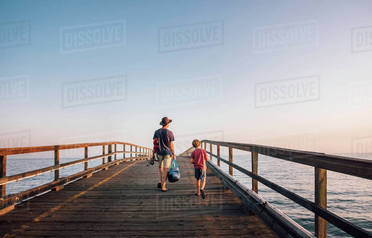 Rear View Of Father And Son Walking On Pier Goleta California Rear View Of Father And Son Walking On Pier Goleta California United States North America