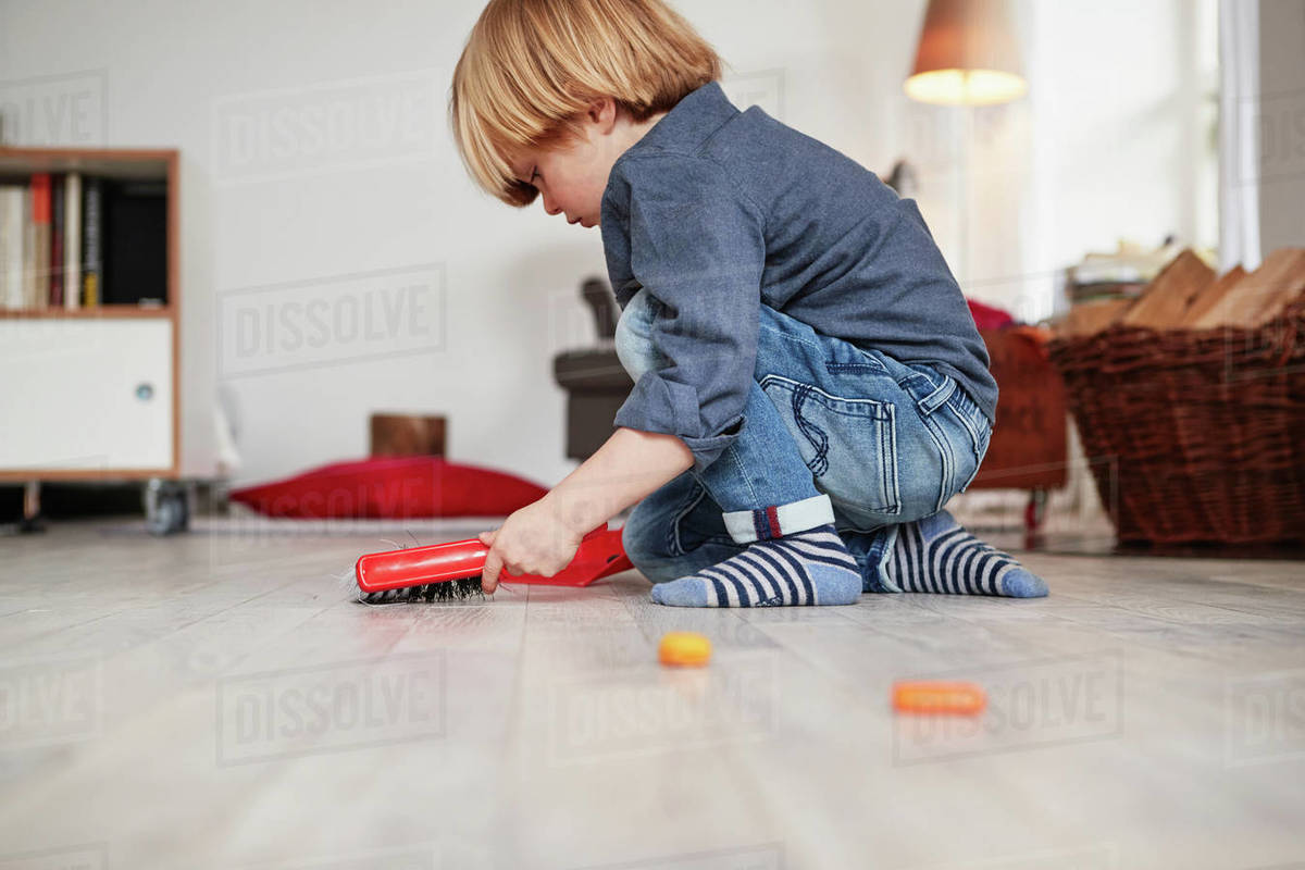 Young boy playing with toy dustpan and brush Stock Photo Dissolve