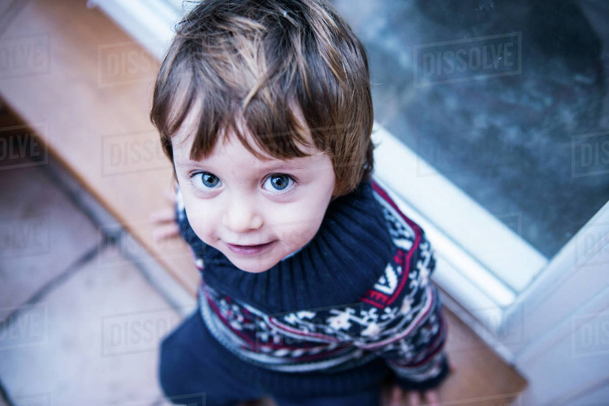 Boy sitting by patio door Stock Photo Dissolve