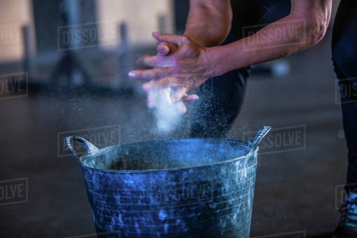 Woman in gymnasium, dusting hands with chalk, mid section Stock Photo