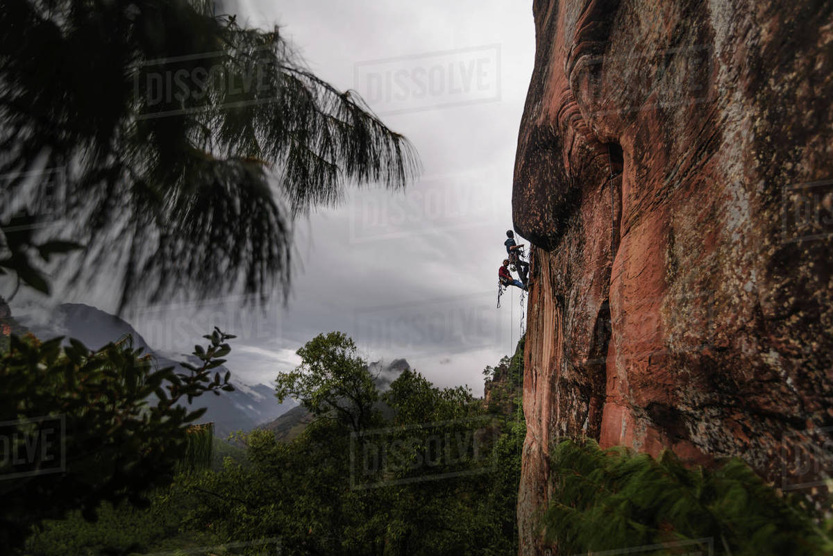 Rock climber climbing sandstone rock, low angle view, Liming, Yunnan