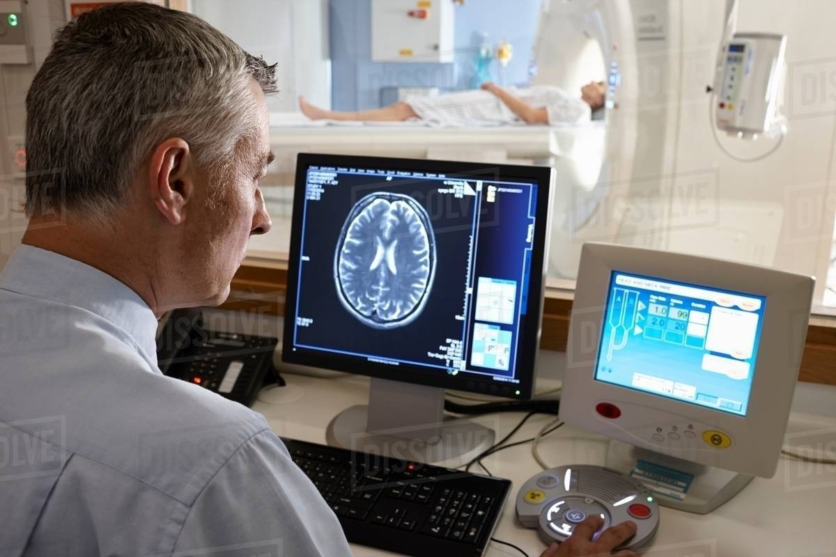 Radiologist looking at brain scan image on computer screen - Stock ...
