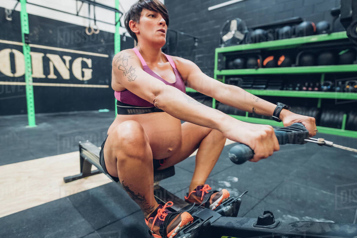 Pregnant woman on rowing machine in gym Stock Photo Dissolve