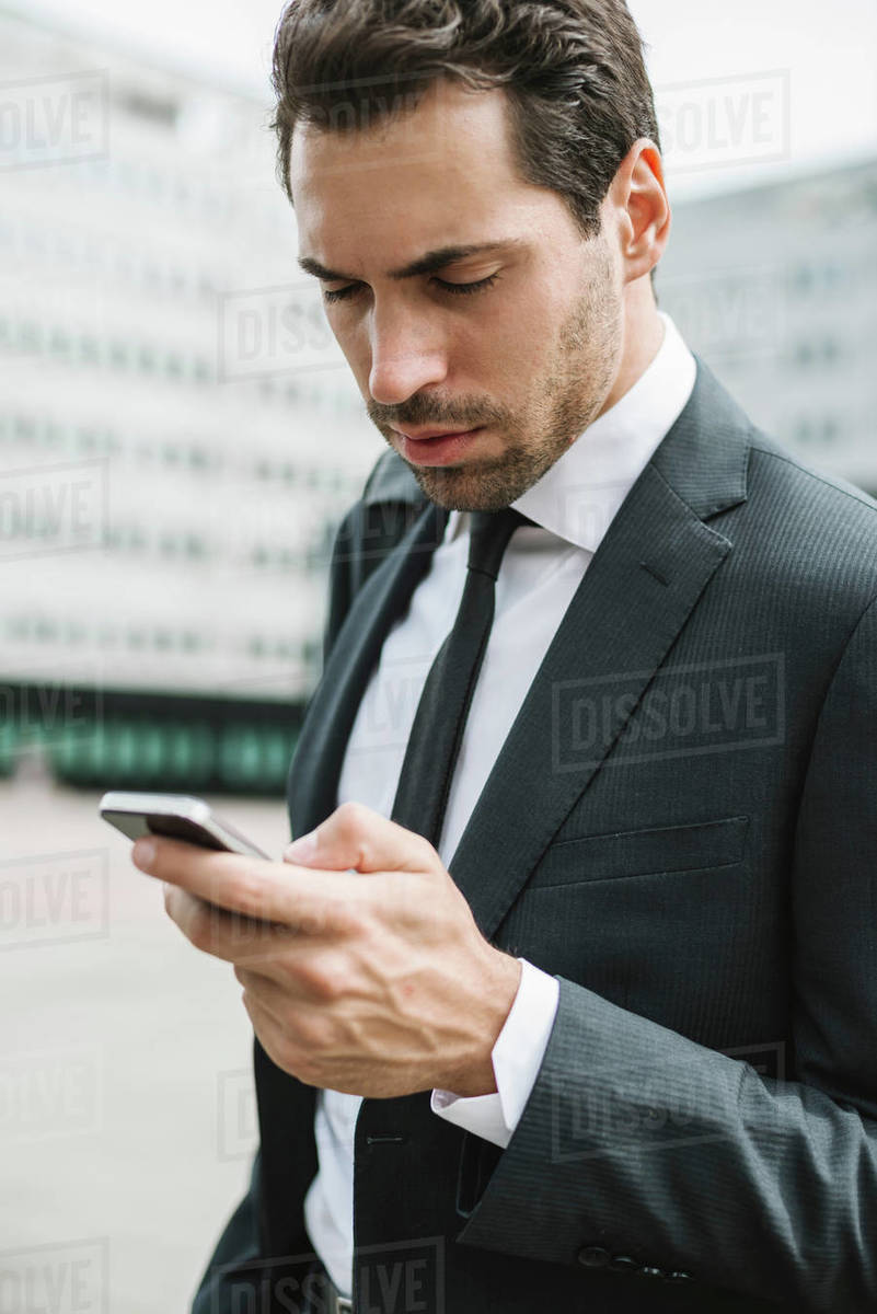 Mid adult businessman outside office building looking at smartphone, close up Royalty-free stock photo