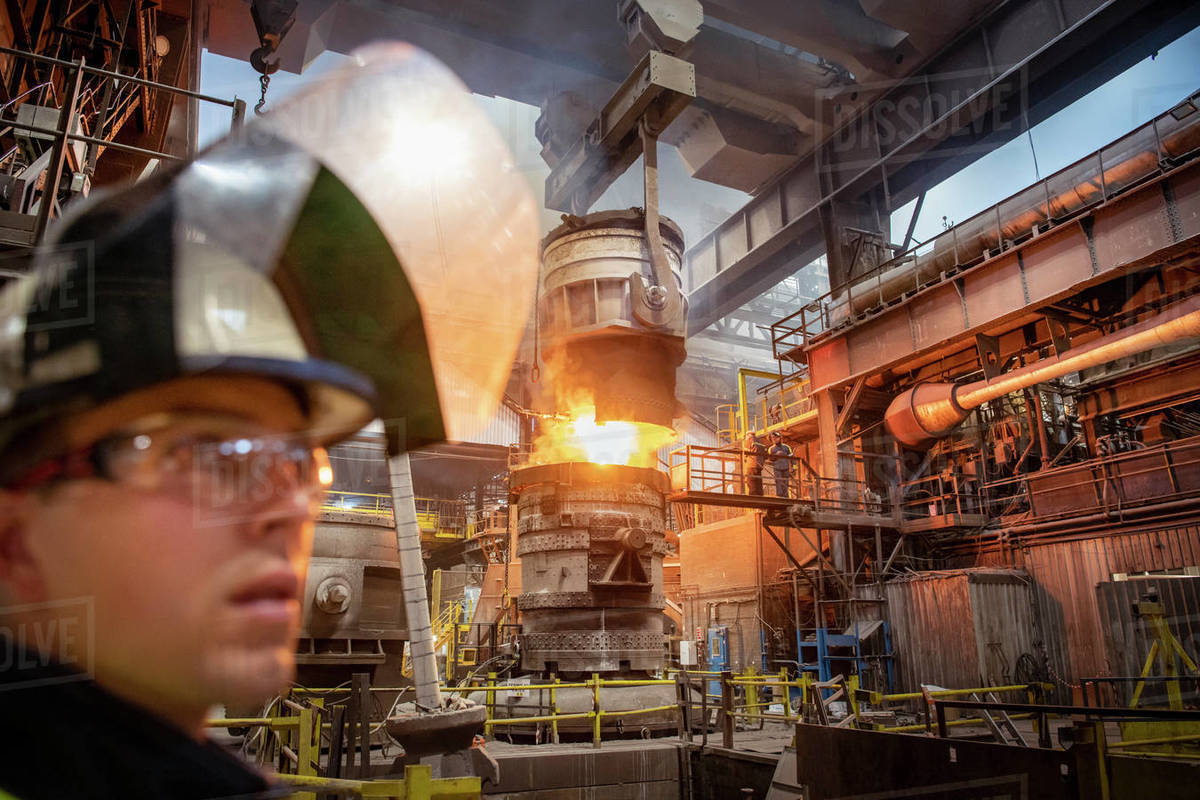 Apprentice steelworker in foreground during molten steel pour in steelworks Royalty-free stock photo