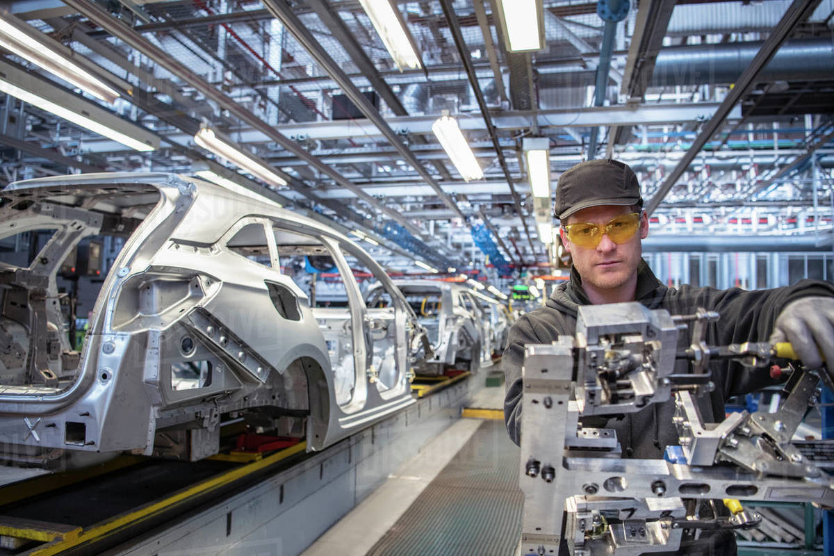 Car worker fitting parts on production line in car factory Royalty-free stock photo