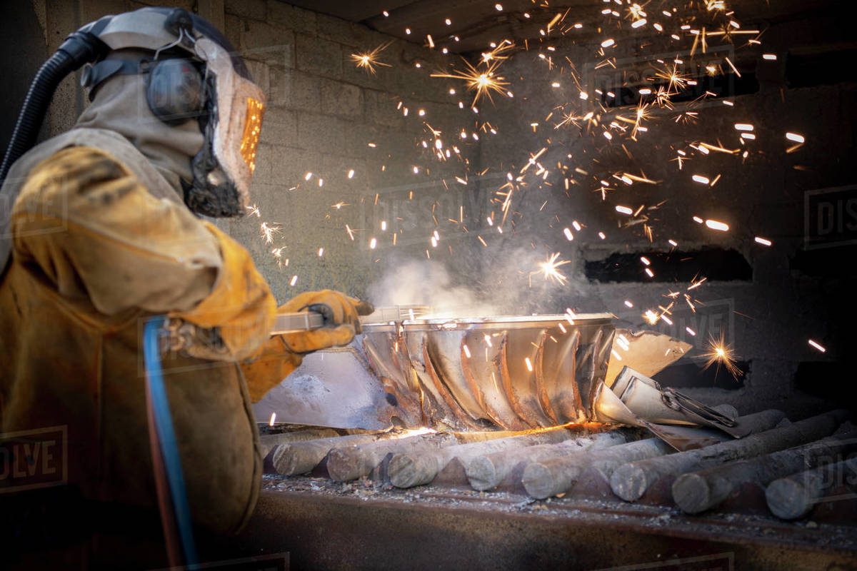Worker cutting up scrap titanium aircraft parts in titanium recycling plant Royalty-free stock photo