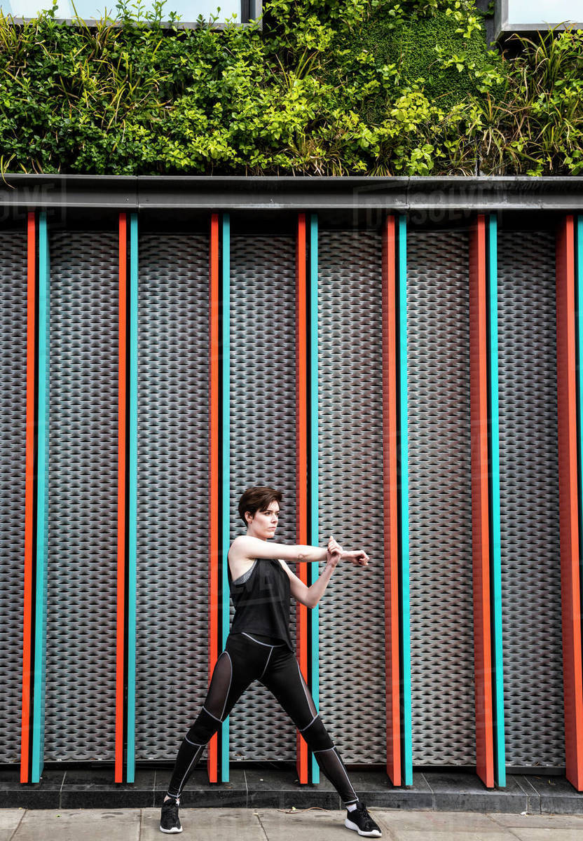 Young woman practicing yoga on city sidewalk, full length Royalty-free stock photo