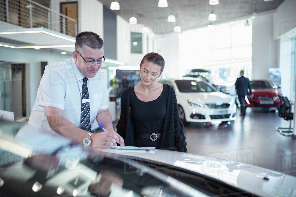 Salesman showing literature to customer in car dealership Royalty-free stock photo