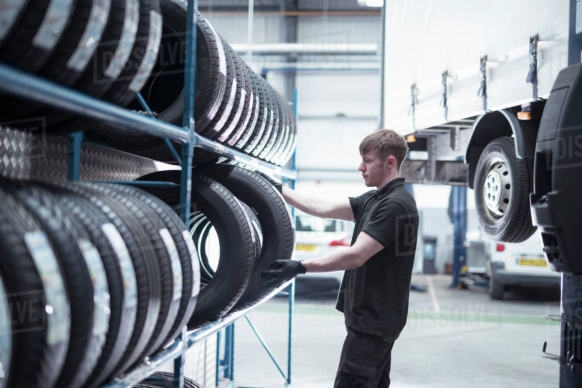 Apprentice engineer selecting tyres in car service centre Royalty-free stock photo